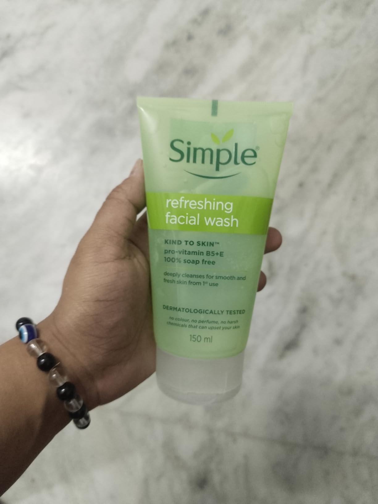Simple Kind To Skin Refreshing Facial Wash 150ml tube held in hand, 100% soap-free face wash suitable for all skin types.